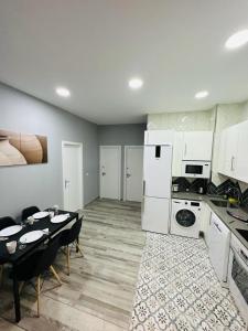 eine Küche und ein Esszimmer mit einem Tisch und weißen Geräten in der Unterkunft HOSPEDAJE CORREDOR DE HENARES in Torrejón de Ardoz