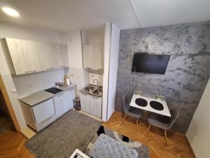 uma pequena cozinha com armários brancos e uma televisão na parede em Dado apartman em Kraljevo