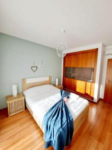 ein Schlafzimmer mit einem großen Bett mit einer blauen Decke darauf in der Unterkunft Apartamento Vila Rosa - PRAIA DA ROCHA in Portimão