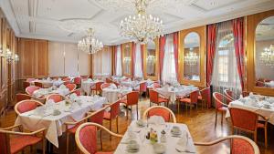 een restaurant met witte tafels en stoelen en kroonluchters bij Hotel Bayerischer Hof Dresden in Dresden