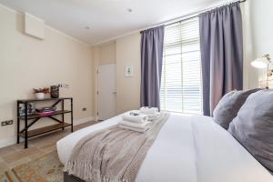 a bedroom with a white bed with towels on it at Bright Groundfloor 3BR Flat, Brockley, SE London in London