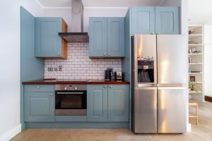 a kitchen with blue cabinets and a stainless steel refrigerator at Bright Groundfloor 3BR Flat, Brockley, SE London in London