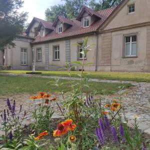un jardin avec des fleurs en face d'une maison dans l'établissement Dworek Cieszków, à Cieszków