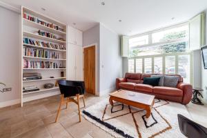 a living room with a red couch and a table at Bright Groundfloor 3BR Flat, Brockley, SE London in London