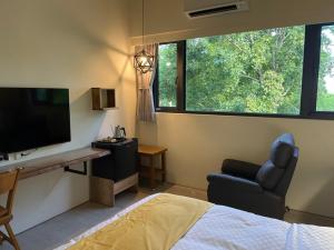 a bedroom with a bed and a tv and a chair at Taroko 767 Farm B&B 太魯閣767農莊民宿 in Xiulin