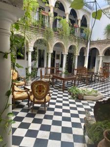 un patio con sillas y mesas en un suelo a cuadros en Hostal Palacio del Corregidor, en Córdoba