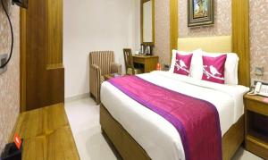 um quarto com uma cama grande e almofadas cor-de-rosa em FabHotel Prime The Vijay Park em Chennai