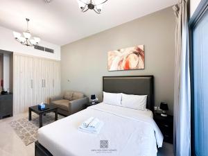um quarto com uma grande cama branca e uma cadeira em Studio with burj view at Elite Business bay Residence by ANW vacation homes em Dubai