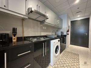 uma cozinha com um fogão e uma máquina de lavar roupa em Studio with burj view at Elite Business bay Residence by ANW vacation homes em Dubai