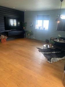 a living room with a wooden floor and a flat screen tv at Trivelig villa med innendørs peis in Fredrikstad