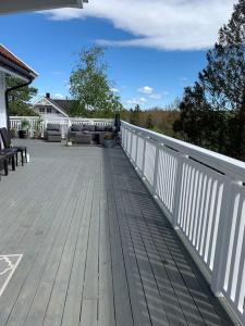 eine Holzterrasse mit einem weißen Zaun auf einem Haus in der Unterkunft Trivelig villa med innendørs peis in Fredrikstad