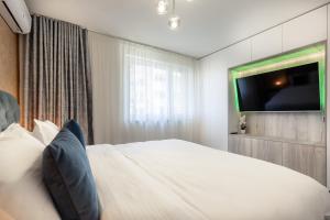 a bedroom with a white bed with a flat screen tv at 5th Floor Executive Apartment with Balcony and Free Parking in Braşov