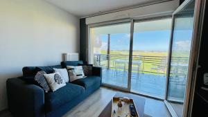 sala de estar con sofá azul y balcón en Appartement vue Baie de Canche - Dundee 2, en Étaples