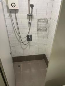 a shower in a bathroom with white tiles at Stay Wanglang in Bangkok