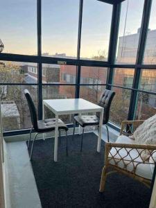 a white table and chairs in a room with windows at Modern and Cozy apartment with Sauna2 in Espoo