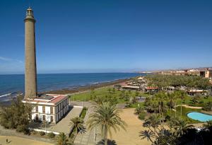 einem Leuchtturm vor dem Meer und einem Resort in der Unterkunft Las Adelfas South Beach 2 By CanariasGetaway in San Bartolomé de Tirajana
