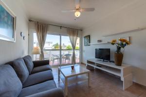ein Wohnzimmer mit einer Couch, einem Fernseher und einem Tisch in der Unterkunft Las Adelfas South Beach 5 By CanariasGetaway in San Bartolomé de Tirajana