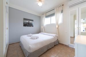ein Schlafzimmer mit einem Bett mit weißen Laken und einem Fenster in der Unterkunft Las Adelfas South Beach 5 By CanariasGetaway in San Bartolomé de Tirajana