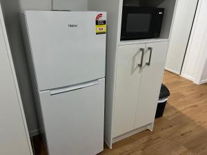 a white refrigerator next to a cabinet with a microwave at Spacious 4 bedroom House in Manukau in Auckland