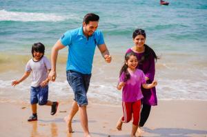 mężczyzna i dwoje dzieci biegających po plaży w obiekcie Destination Beach Hotel by Dreamworld w mieście Karaczi