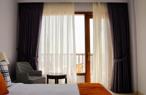 a bedroom with a bed and a window with a chair at Destination Beach Hotel by Dreamworld in Karachi
