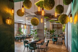 een restaurant met tafels en stoelen en hanglampen bij Hotel Cztery Pory Roku in Głogów Małopolski