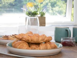 a plate of croissants and pastries on a table at Pass the Keys River View Snowdonia Town Apartment in Bethesda