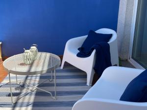 Habitación con mesa, sillas y pared azul. en Apartamento con vistas al mar Urb Puerto Azul B5, en Cedeira