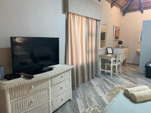 a living room with a flat screen tv on a dresser at Loch Athlone Overnight Accommodation in Bethlehem