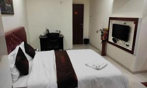 1 dormitorio con 1 cama grande y TV en FabHotel Prime Finesse en Kharadi