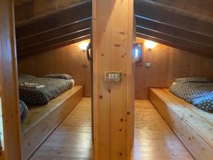 2 łóżka piętrowe w pokoju z drewnianymi ścianami w obiekcie CHALET JOEN ski & bike Andalo w Andole