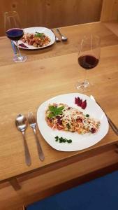 two plates of food on a wooden table with wine glasses at Villa Ilex - Ein Massivholzhaus direkt am See in Görlitz