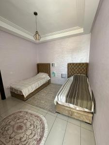 1 Schlafzimmer mit 2 Betten und einem Teppich in der Unterkunft Appartement de luxe sécurisée, calm, privée avec piscine in El Jadida