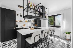 een keuken met een zwart eiland met barkrukken bij Villa Chou Chou in Steinhaus am Semmering