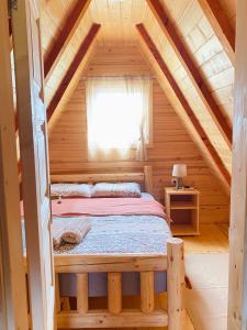a bed in a log cabin with a window at Red Rock in Žabljak