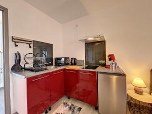 - une cuisine avec des placards rouges et un évier dans l'établissement Joli studio Le Rosa Bonheur, proche de la gare, à Yzeure