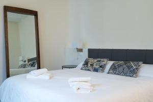 une chambre avec un grand lit blanc avec des serviettes dessus dans l'établissement Nueva casa boutique en el centro de Sevilla, à Séville