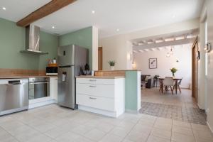 uma cozinha com paredes verdes e utensílios de aço inoxidável em La Maison des Délices em Dosches
