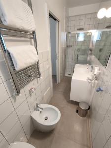 a white bathroom with a toilet and a sink at QuiHotel in Porto Cesareo