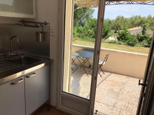 d'une cuisine avec une porte coulissante en verre s'ouvrant sur une terrasse. dans l'établissement Appartement dans bastide à Saint Rémy de Provence, à Saint-Rémy-de-Provence