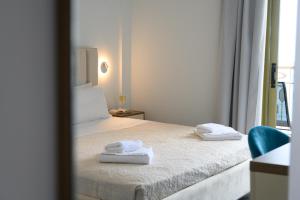 1 dormitorio con 1 cama con 2 toallas en Ninos Grand Beach Resort, en Kastrosikia