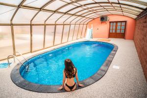 a woman sitting in front of a swimming pool at Penzion Charlie in Mohelnice