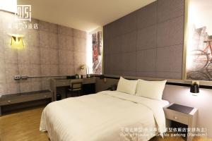 a bedroom with a large white bed and a desk at Military 75 Hotel in Taichung