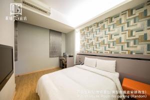 a bedroom with a large white bed and a wall at Military 75 Hotel in Taichung