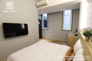 1 dormitorio con 1 cama y TV de pantalla plana en Military 75 Hotel en Taichung