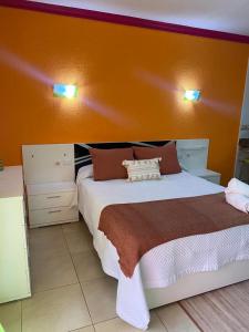 una camera con un grande letto con una parete arancione di ARCOIRIS AL MAR a San Marcos