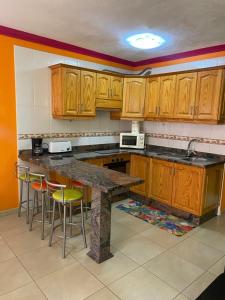 Una cocina con gabinetes de madera y un mostrador con taburetes. en ARCOIRIS AL MAR, en San Marcos
