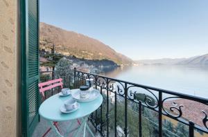 einen Tisch auf einem Balkon mit Blick auf das Wasser in der Unterkunft Villa Peroni Lake Como Vintage in Argegno