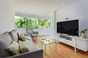 Sala de estar con sofá gris y TV en Golden Bay Apartment en Estepona