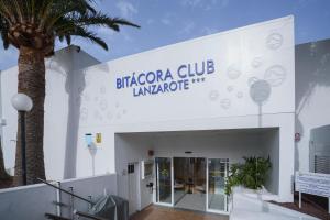 un edificio con una palma di fronte di Bitacora Lanzarote Club a Puerto del Carmen